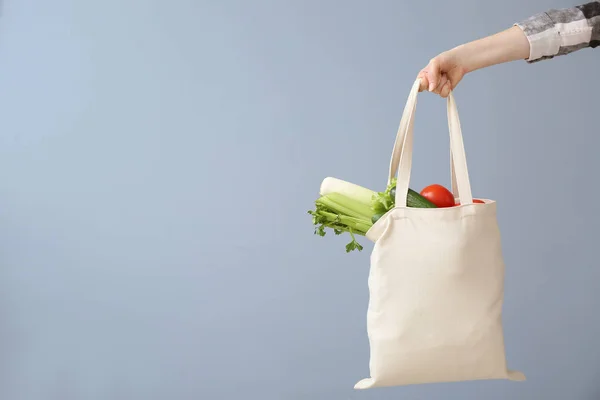 Vrouwelijke hand met Eco-tas op grijze achtergrond. Zero Waste concept — Stockfoto