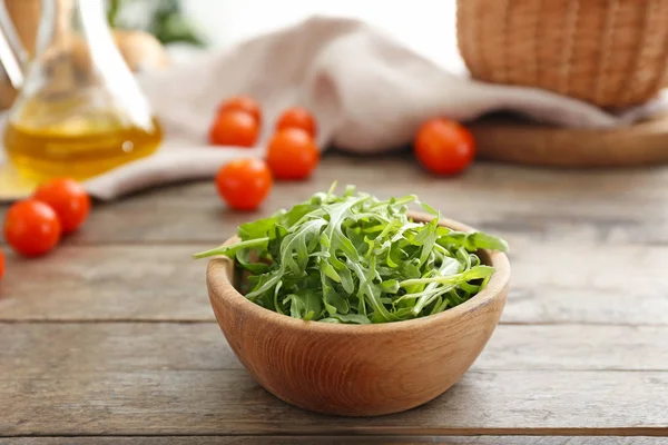 Kom met lekkere verse rucola op houten tafel — Stockfoto