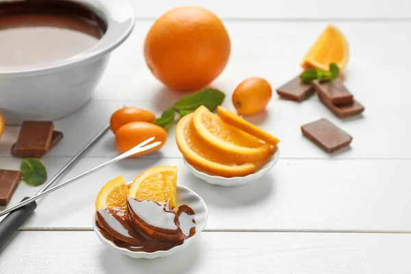 Fresh orange slices with melted chocolate on white table — Stock Photo, Image