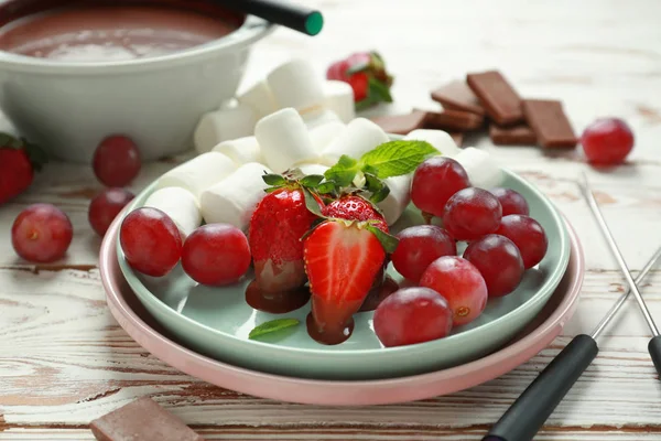 Bord met vers fruit, marshmallow en gesmolten chocolade op witte tafel — Stockfoto