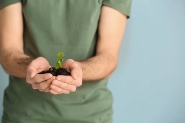 Renkli arka planda genç bitki ile Adam, closeup