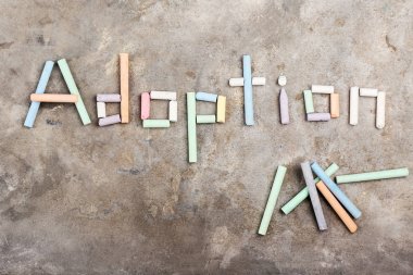 Gri arkaplandaki boya kalemlerinden oluşan kelime evlat edinme