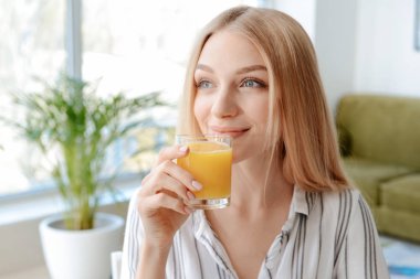 Güzel genç bayan evde taze meyve suyu içiyor.
