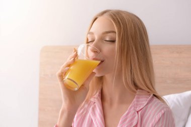 Güzel genç kadın yatakta taze meyve suyu içme