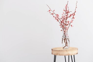 Masanın üzerinde çiçek açan güzel dalları olan bir vazo.