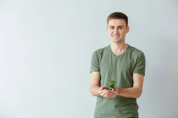 Hombre con planta joven sobre fondo claro — Foto de Stock