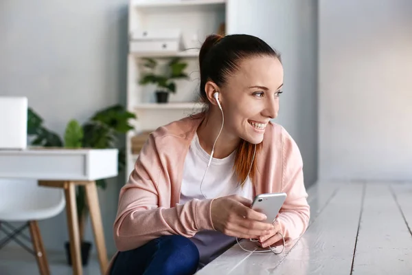 Woman with mobile phone listening to music indoors — Stock Photo, Image