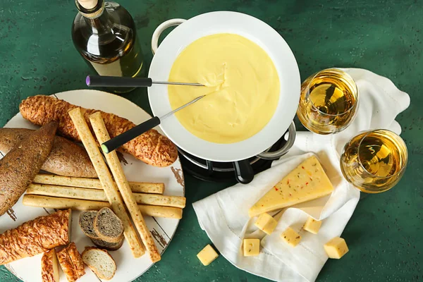 Fondue de queso con aperitivos y vino sobre fondo de color —  Fotos de Stock