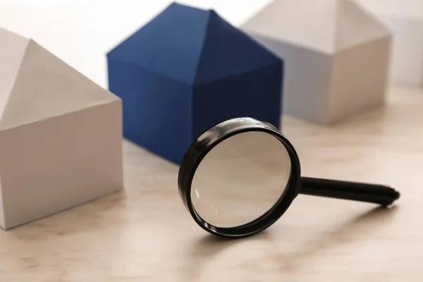 Paper models of houses and magnifier on table — Stock Photo, Image