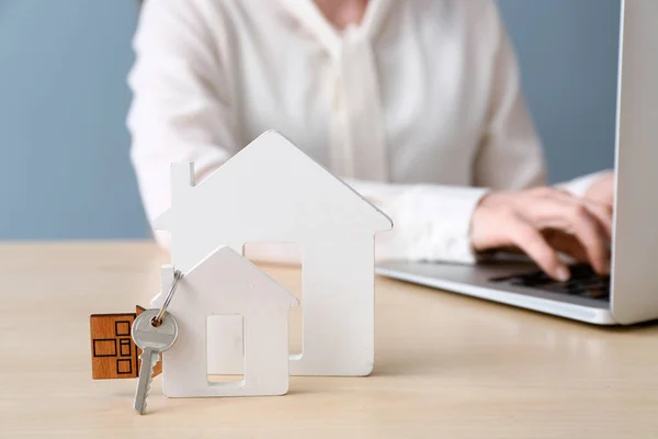 Figures of houses and key on table of real estate agent — Stock Photo, Image