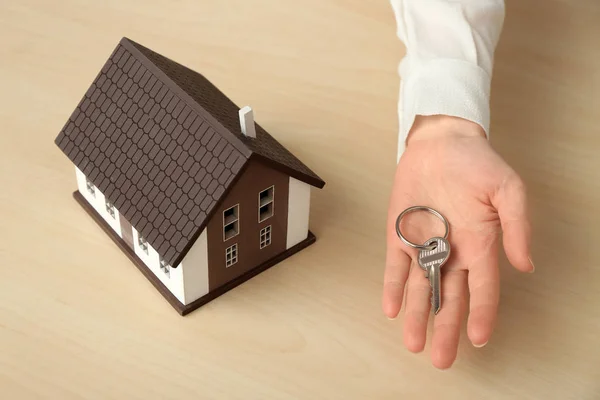 Immobilienmakler mit Schlüssel und Hausmodell am Tisch — Stockfoto
