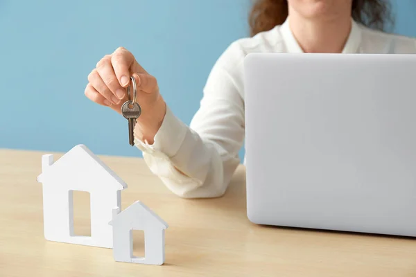 Immobilienmakler mit Schlüssel, Laptop und Häuserfiguren am Tisch — Stockfoto