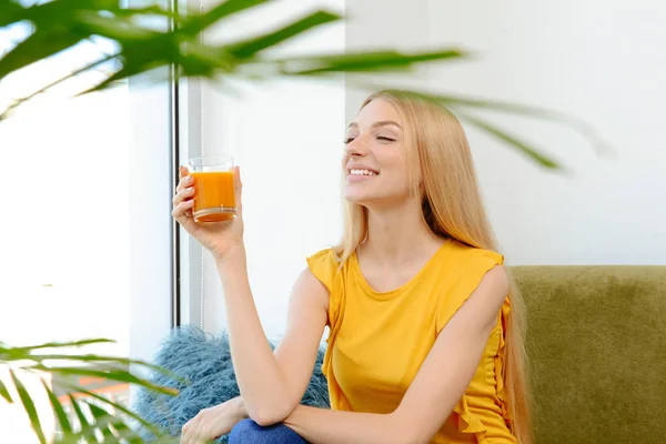 Hermosa joven bebiendo jugo fresco en casa — Foto de Stock