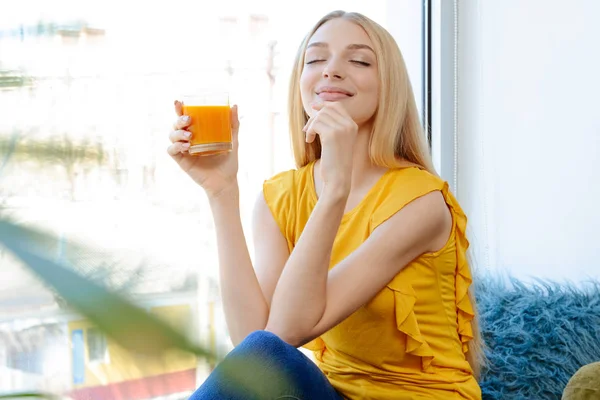 Hermosa joven bebiendo jugo fresco en casa — Foto de Stock