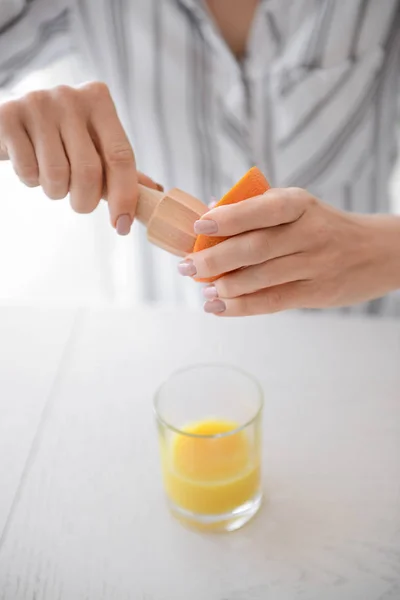 Красивая молодая женщина выжимает сок из апельсина дома, крупным планом — стоковое фото