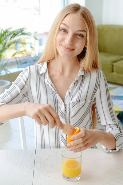 Belle jeune femme serrant du jus d'orange à la maison — Photo