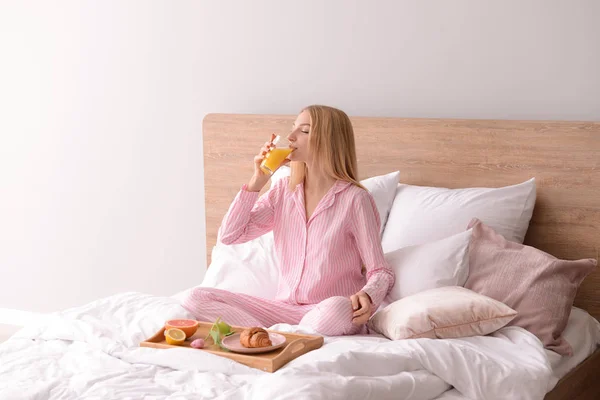 Beautiful young woman having breakfast in bed — Stock Photo, Image