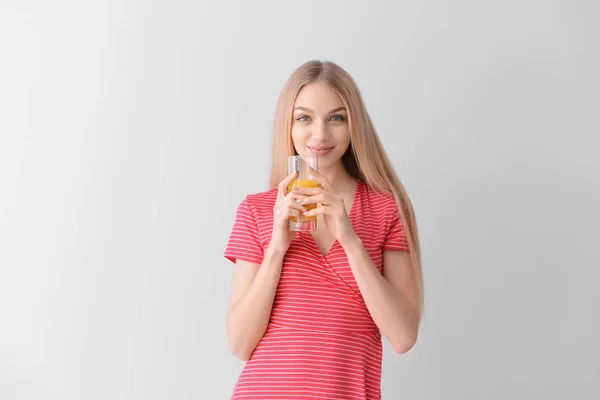 美丽的年轻女子与新鲜果汁在光背景 — 图库照片