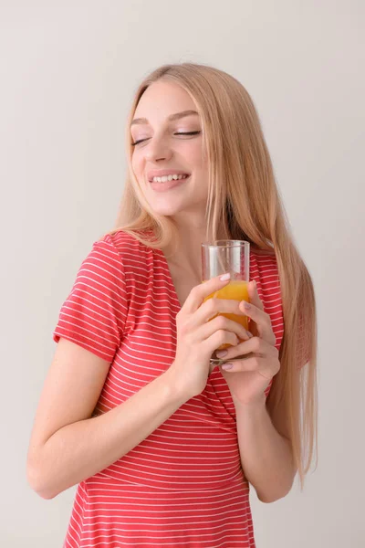 Piękna młoda kobieta ze świeżym sokiem na jasnym tle — Zdjęcie stockowe