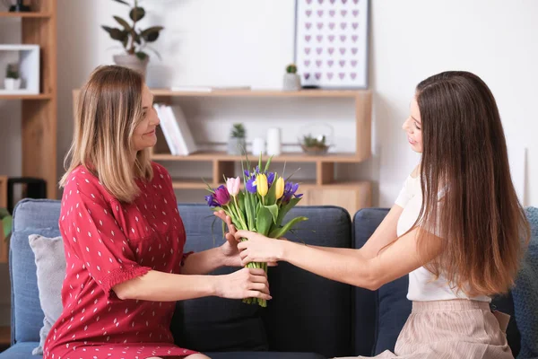 Tochter begrüßt ihre Mutter zu Hause mit Blumen — Stockfoto