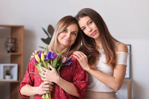 Young woman and her mother with bouquet of flowers at home — Stock Photo, Image