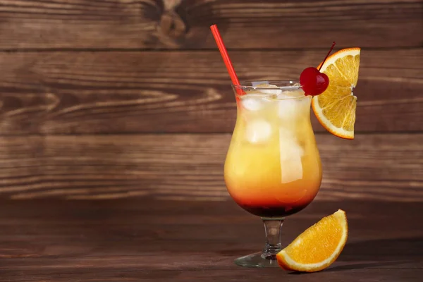 Glass of tasty Tequila Sunrise cocktail on wooden background — Stock Photo, Image