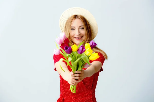 Portrait of mature woman with flowers on light background — Stock Photo, Image