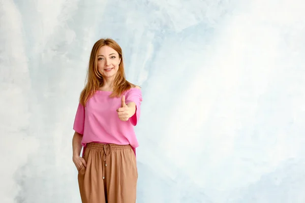 Retrato de mujer madura mostrando el pulgar hacia arriba sobre fondo claro — Foto de Stock