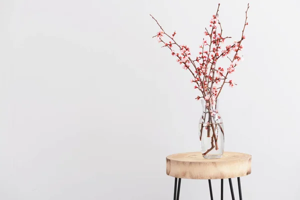 Vaas met mooie bloeiende takken op tafel tegen een lichte achtergrond — Stockfoto