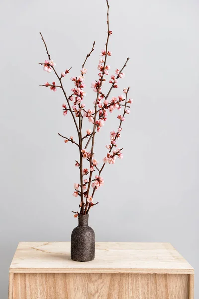 Vase mit schön blühenden Zweigen auf dem Tisch vor hellem Hintergrund — Stockfoto