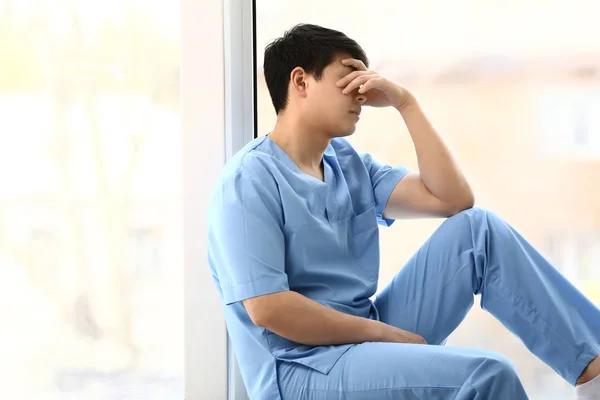 Depressiver Arzthelfer sitzt auf Fensterbank in Klinik — Stockfoto