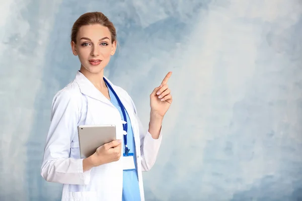 色の背景にタブレットコンピュータを持つ女性医師の肖像画 — ストック写真