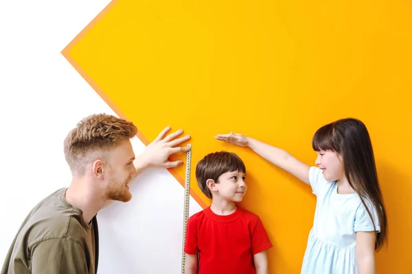 Father and his little children measuring height near wall — Stock Photo, Image