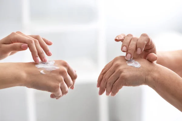 Young and mature women applying hand cream at home — 스톡 사진