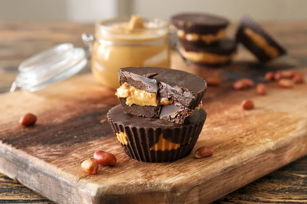 Tasty chocolate peanut butter cups on wooden board — Stock Photo, Image