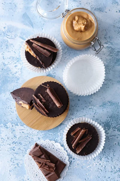 Sabrosas tazas de mantequilla de cacahuete de chocolate sobre fondo de color —  Fotos de Stock