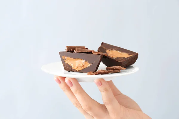 Mano femminile con tazze di burro di cioccolato su sfondo chiaro — Foto Stock