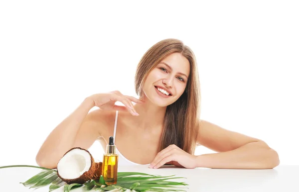 Vacker ung kvinna och kosmetika med kokosextrakt på vit bakgrund — Stockfoto