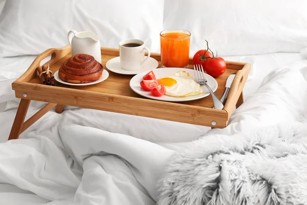 Table with tasty breakfast on bed — Stock Photo, Image