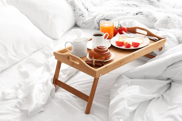 Table with tasty breakfast on bed — Stock Photo, Image