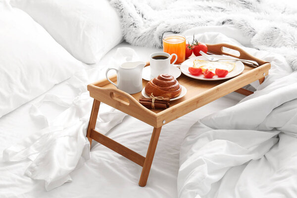 Стол с вкусным завтраком на кровати
