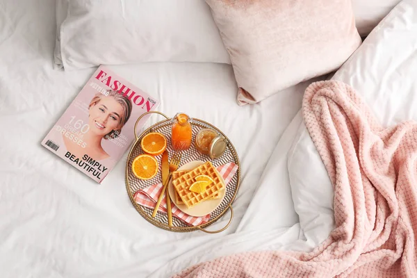 Podnos s chutnou snídaní a módním časopisem na posteli — Stock fotografie
