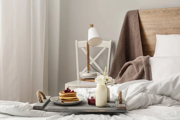 Board with tasty breakfast on bed — Stock Photo, Image