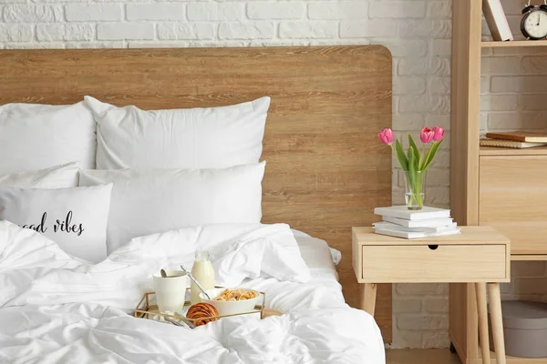 Tray with tasty breakfast on bed in interior of room — Stock Photo, Image