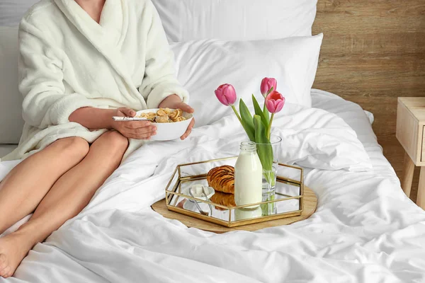 Junge Frau frühstückt auf dem Bett — Stockfoto