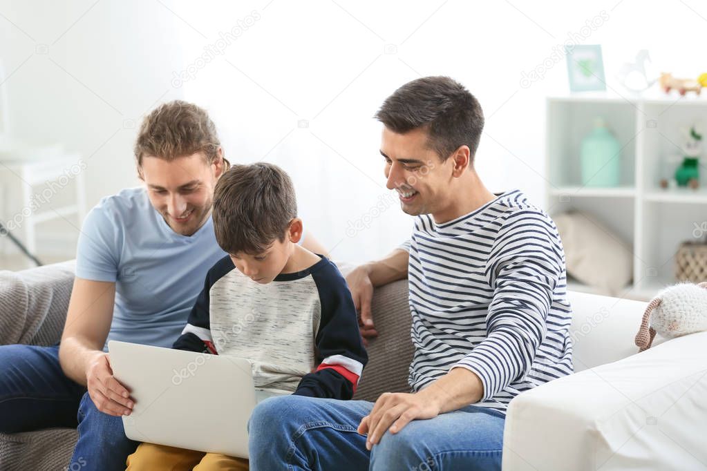 Happy gay couple and adopted child with laptop at home