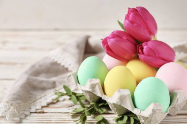 Beyaz ahşap masa üzerinde güzel Paskalya yumurtaları ve çiçekleri ile Paket