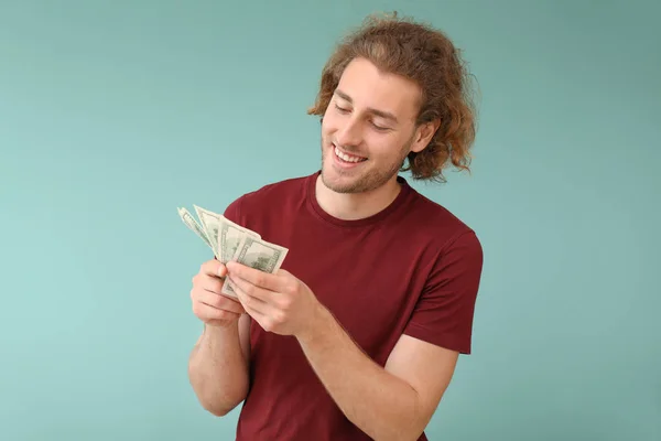 Heureux jeune homme avec des billets en dollars sur fond de couleur — Photo