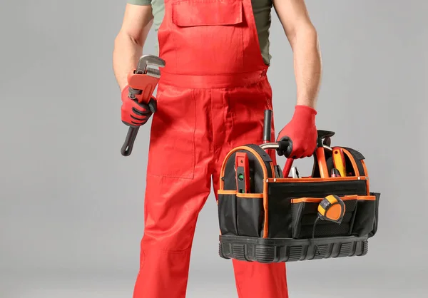 Plumber with tools bag on grey background — Stock Photo, Image