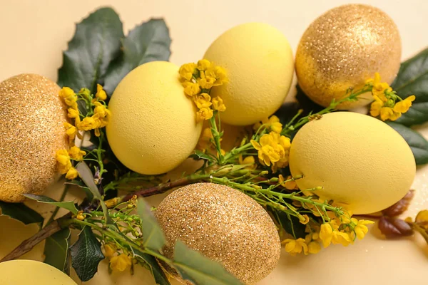 Beautiful Easter eggs with green leaves and flowers on color background — Stock Photo, Image